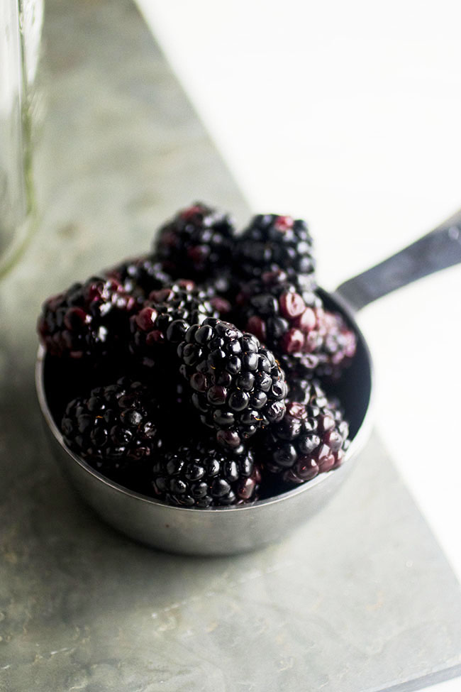 Silver measuring cup filled with fresh blackberries.