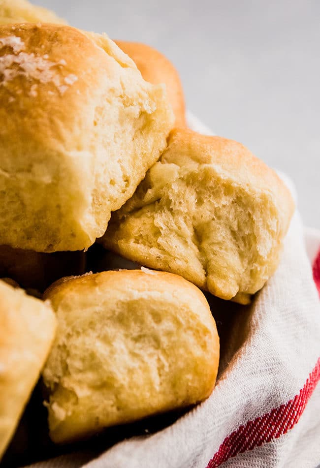 Fresh dinner rolls in a small bowl lined with a white towel.