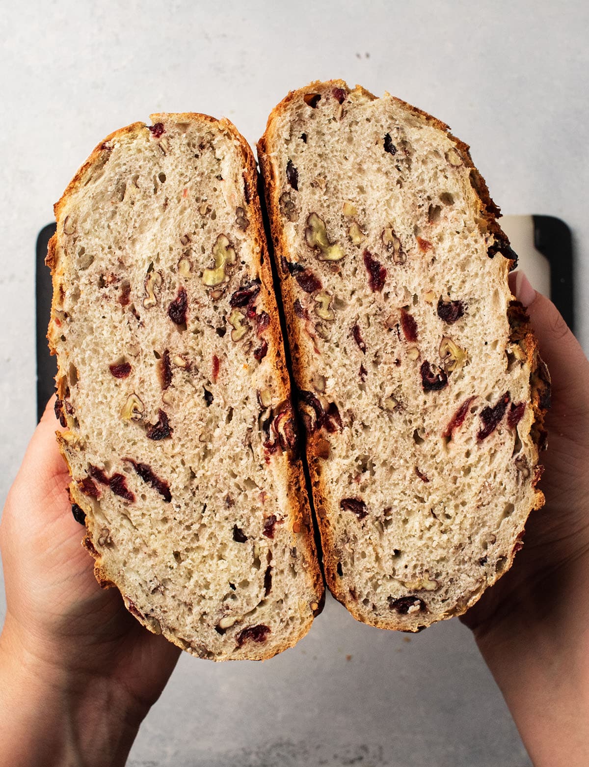 Hands holding two halves of a bread loaf together to show the crumb.