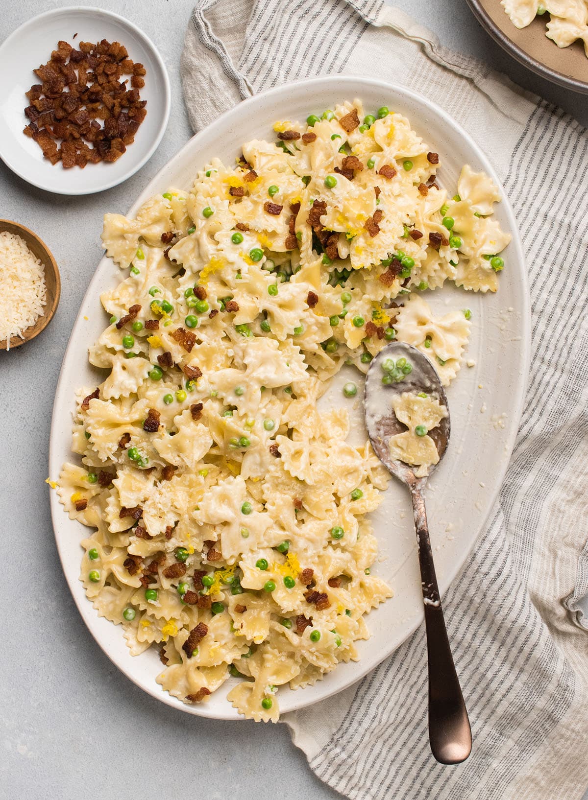 Lemon pasta on a large white serving platter with a copper spoon.