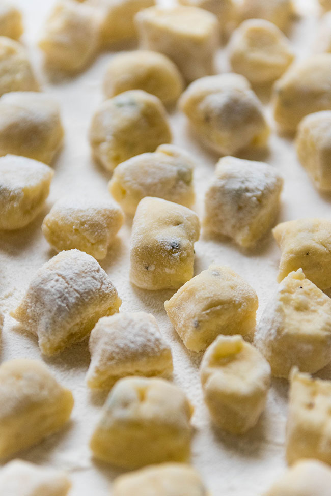 Fresh, uncooked potato gnocchi on a white background.