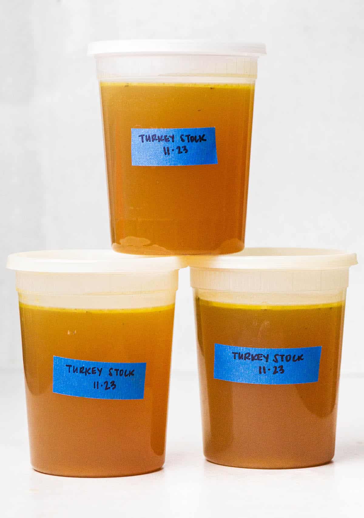 Three containers of homemade turkey stock with blue labels.
