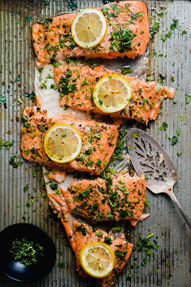 Steelhead trout fillet topped with lemon and parsley and cut into slices.