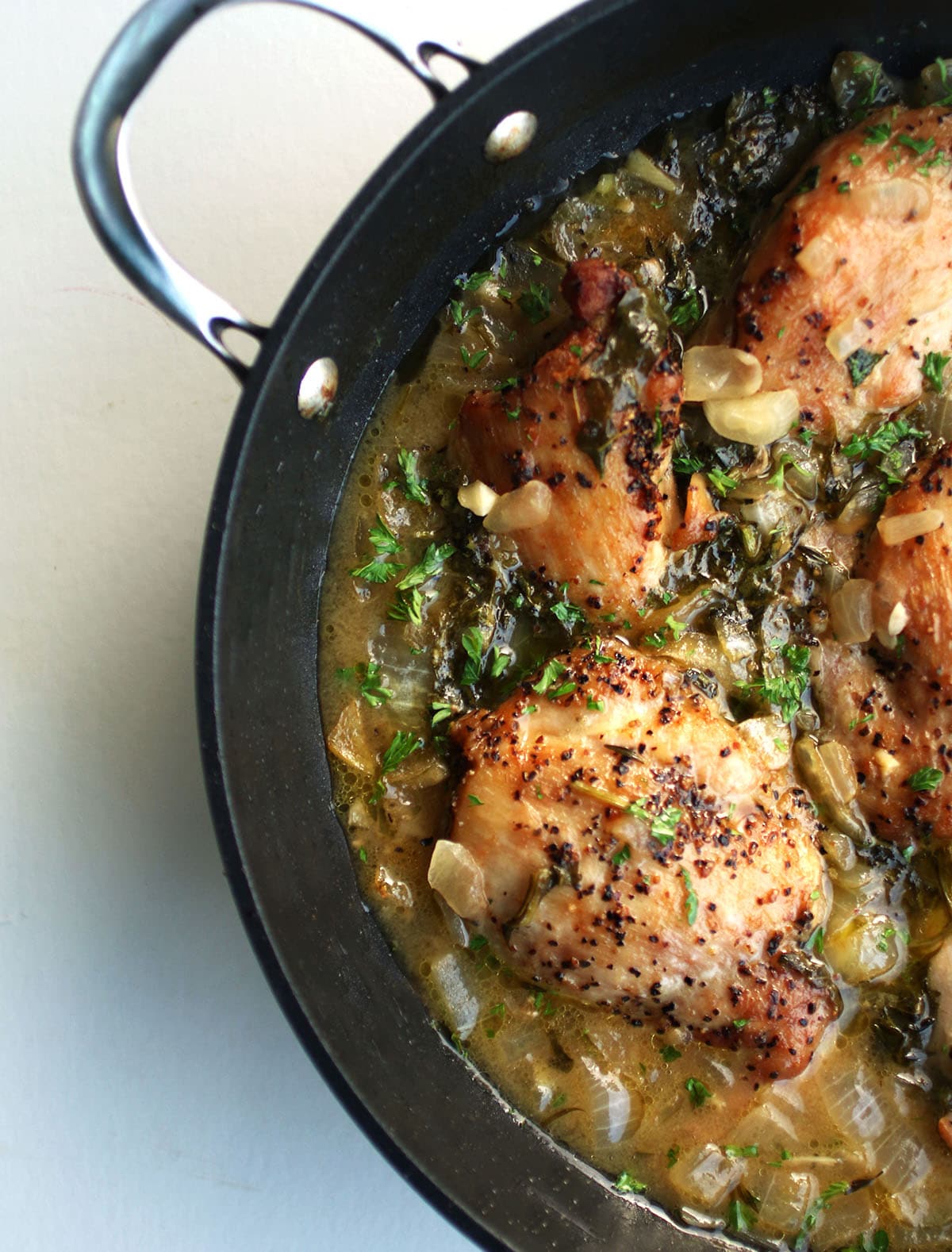 Chicken thighs in a shallow saucepan with lemon broth.