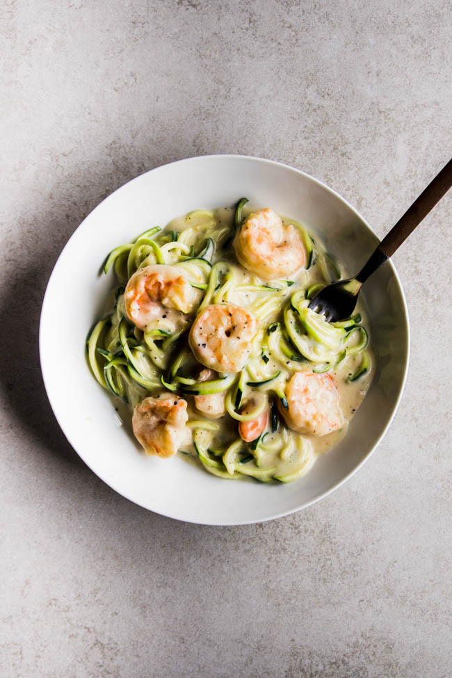 Fork twirling a bite of zucchini noodles with alfredo sauce.