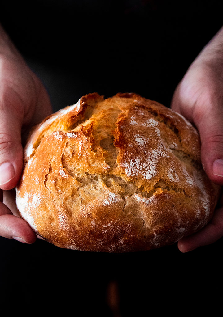 Hands holding a small loaf of bread.
