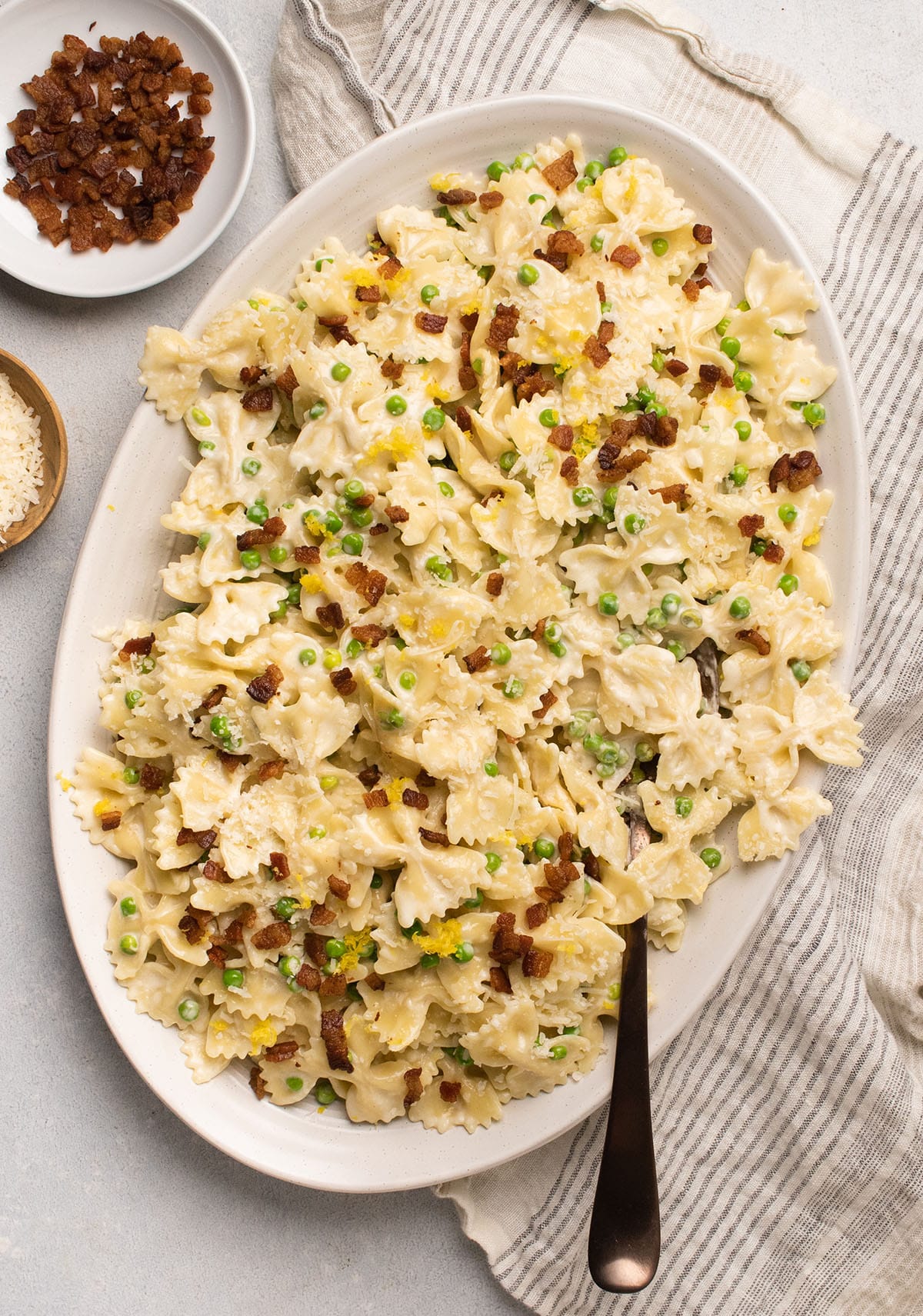 Lemon pasta on a white plate, topped with bacon.