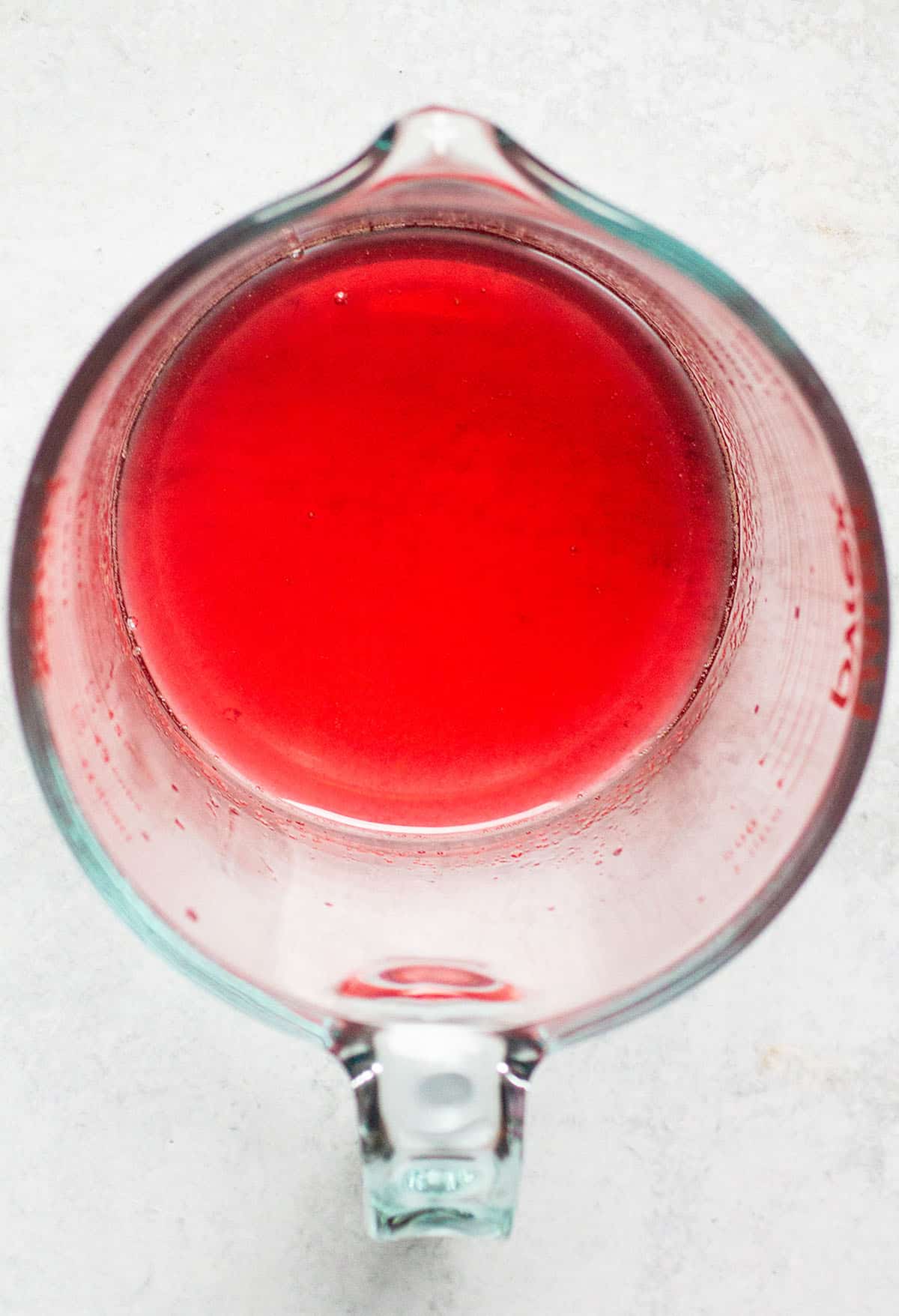 Peach syrup in a large glass measuring cup.