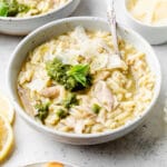 Chicken soup in a white bowl, topped with pesto.