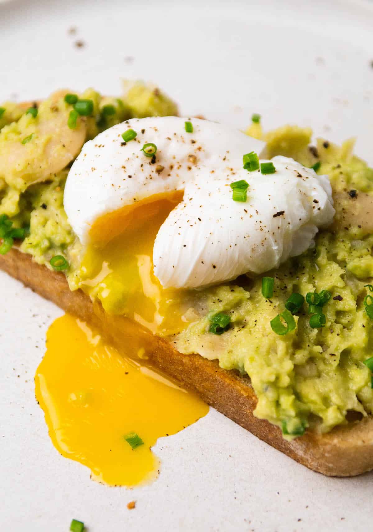 Poached egg with yolk running out on top of avocado toast.