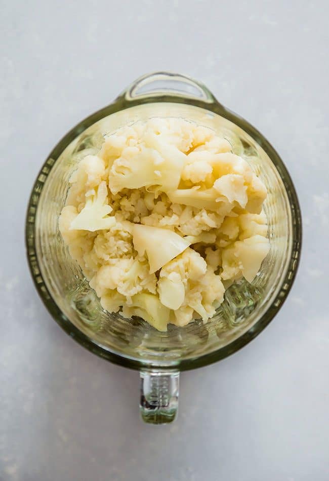 Aerial view of cooked cauliflower florets in a glass blender.
