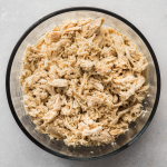 Glass bowl filled with shredded chicken.
