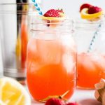 Strawberry cocktails in glass mason jars, garnished with fresh strawberries.