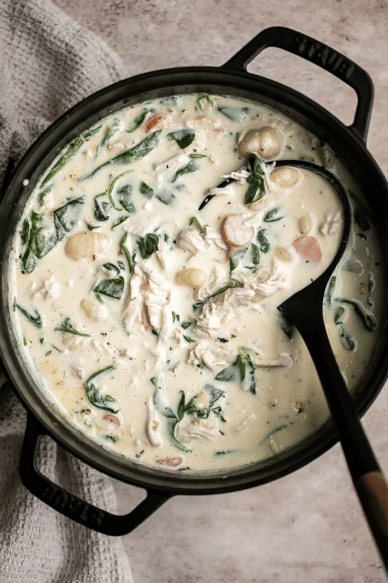 Black ladle scooping gnocchi soup out of a large pot.