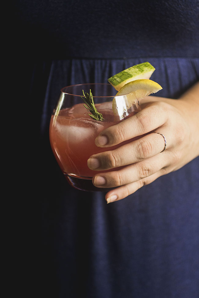 Woman in a blue dress holding a watermelon cocktail.