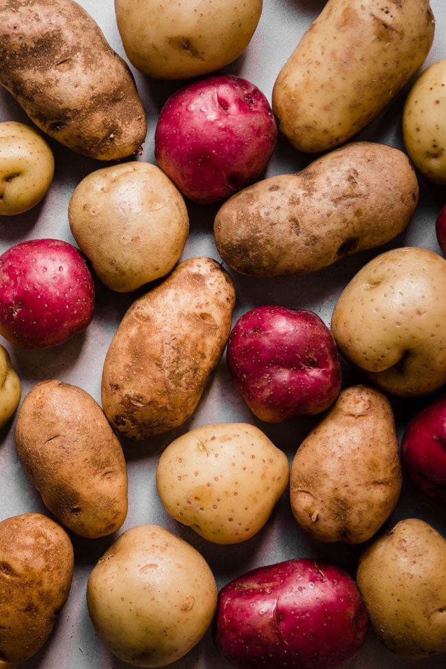 Red, yellow, and russet potatoes arranged on a white background.